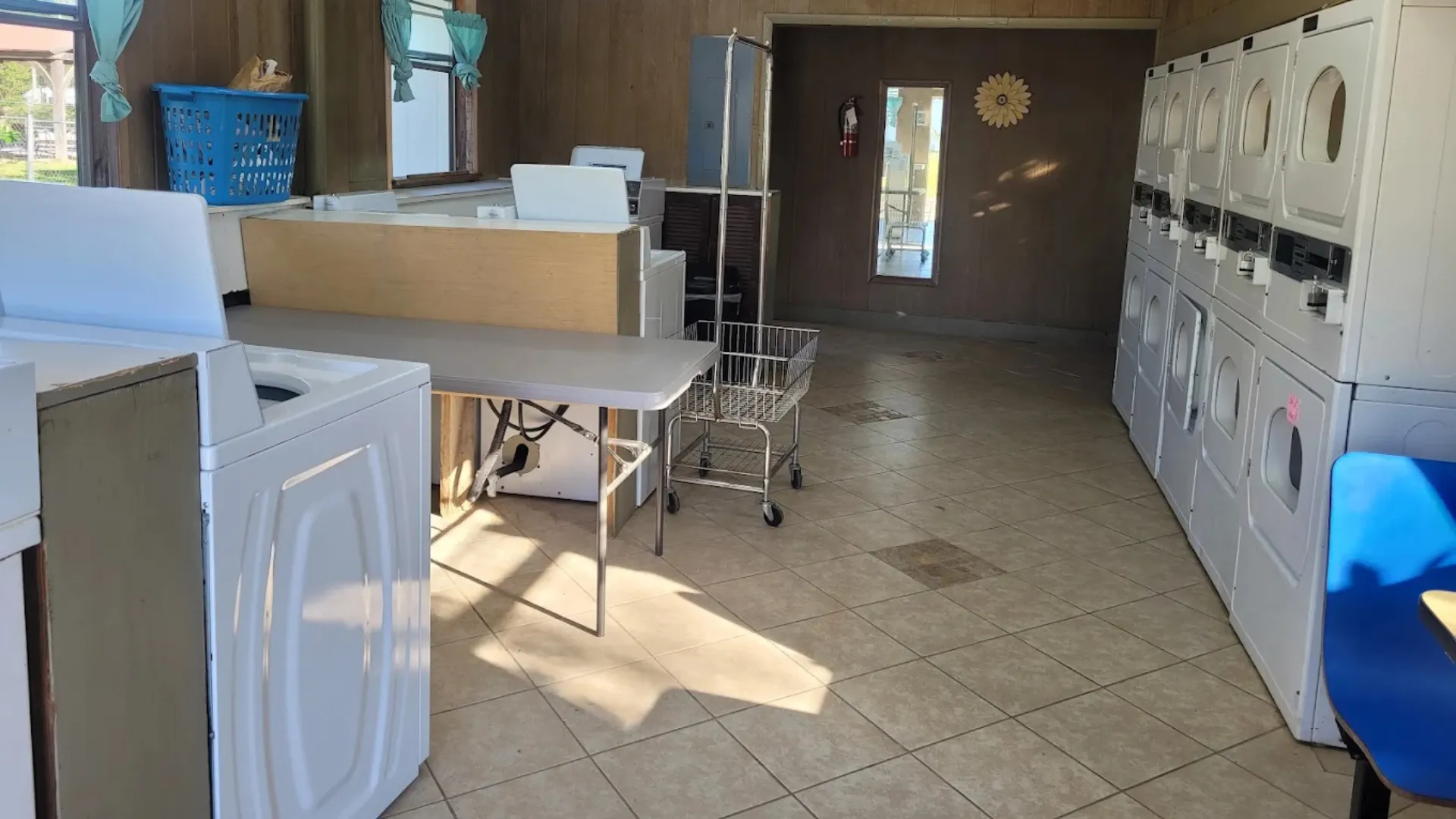 Inside a clean laundry facility at a Tallahassee RV resort with rows of white washing machines, stacked dryers, and a large folding table.